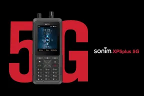 The Sonim XP5plus 5G keypad phone with two knobs on top, its screen showing the time, in front of a large red 5G