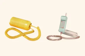 A yellow Tin Can landline next to a mint Waffle Home handset on its base, both on coiled cords
